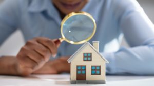 Woman holding magnifying class over house model