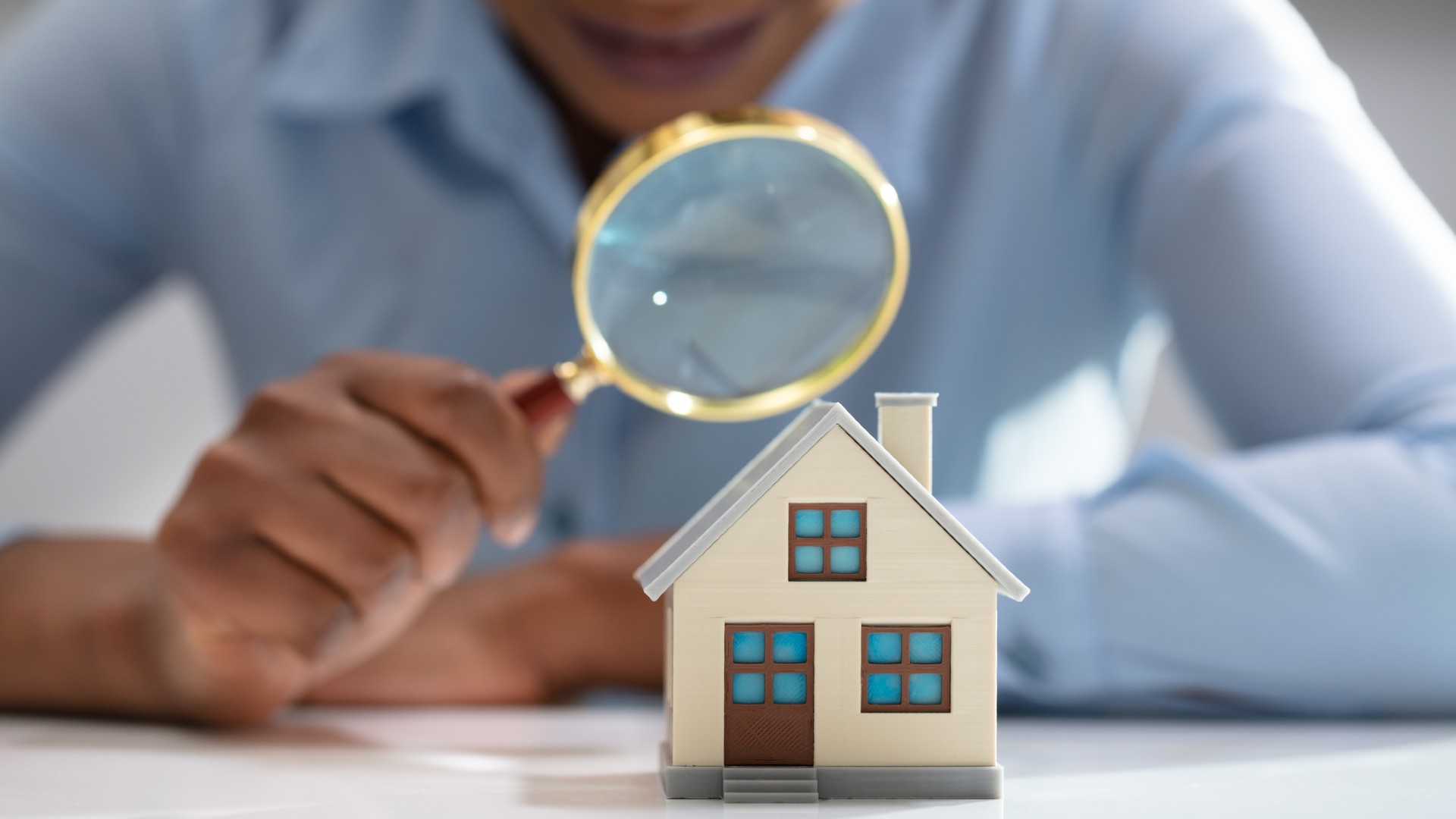 Woman holding magnifying class over house model